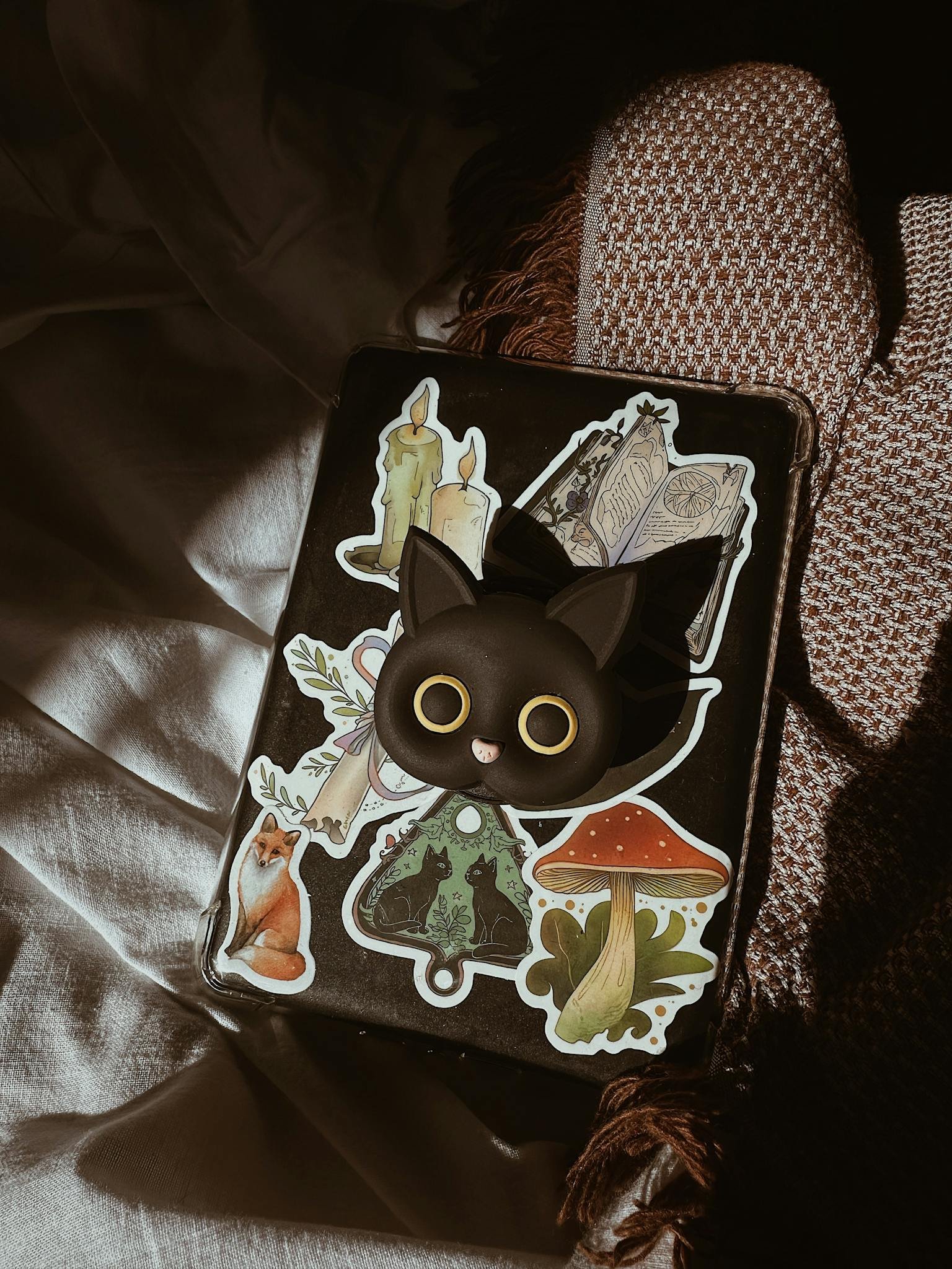 Notebook adorned with playful cat and nature-themed stickers under warm lighting.